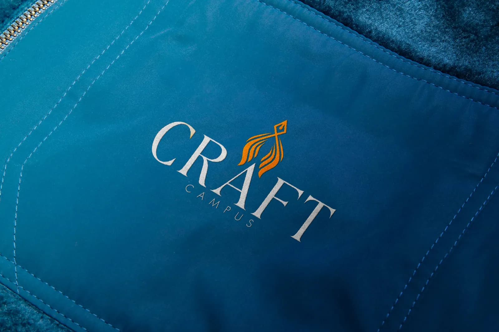 Craft Campus logo with an orange kite mark pressed into blue technical fabric